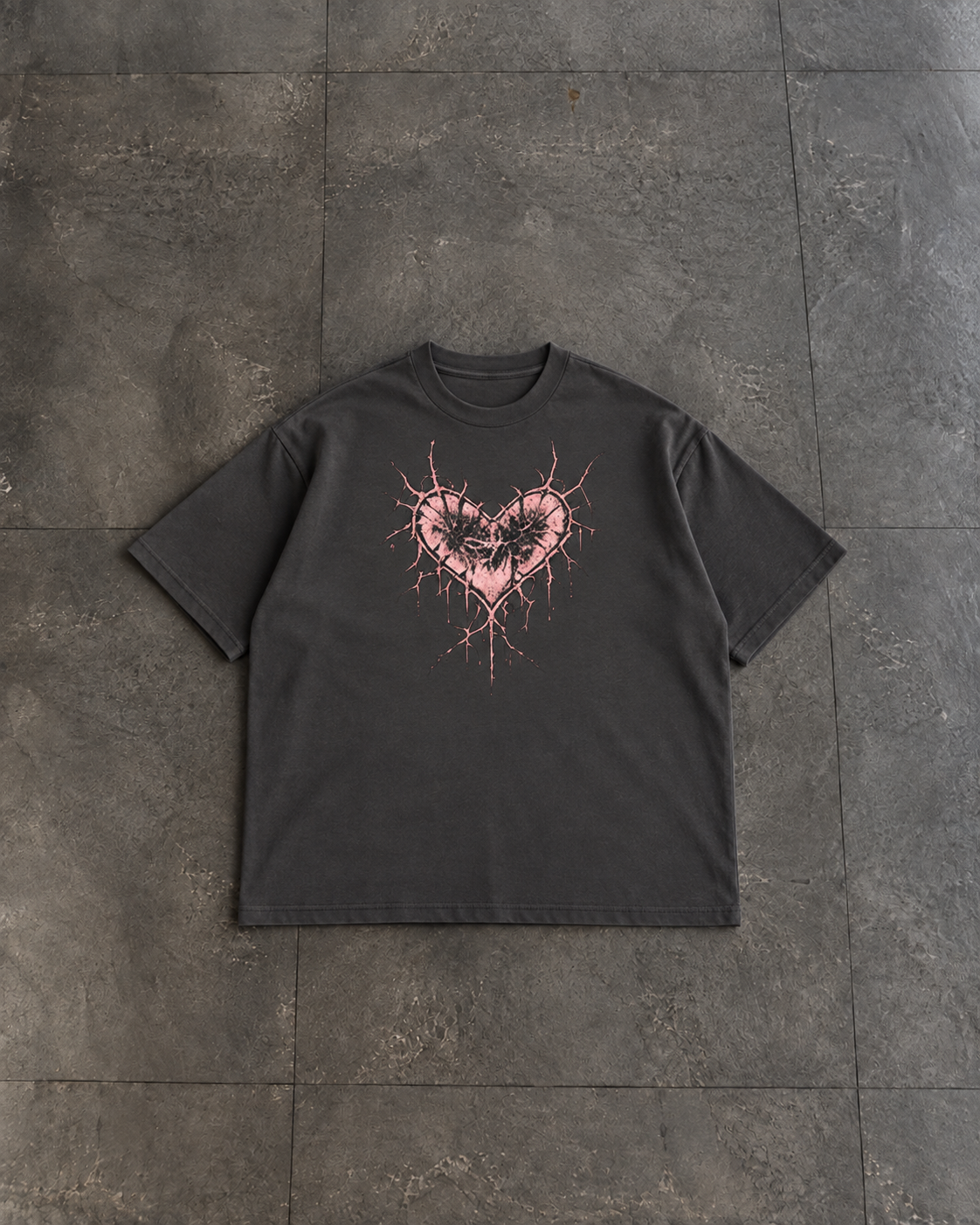 A dark charcoal gray short-sleeve t-shirt with a pink splattered heart graphic on the chest, laid flat on a dark gray tiled surface.

Color: Vintage Black Front 