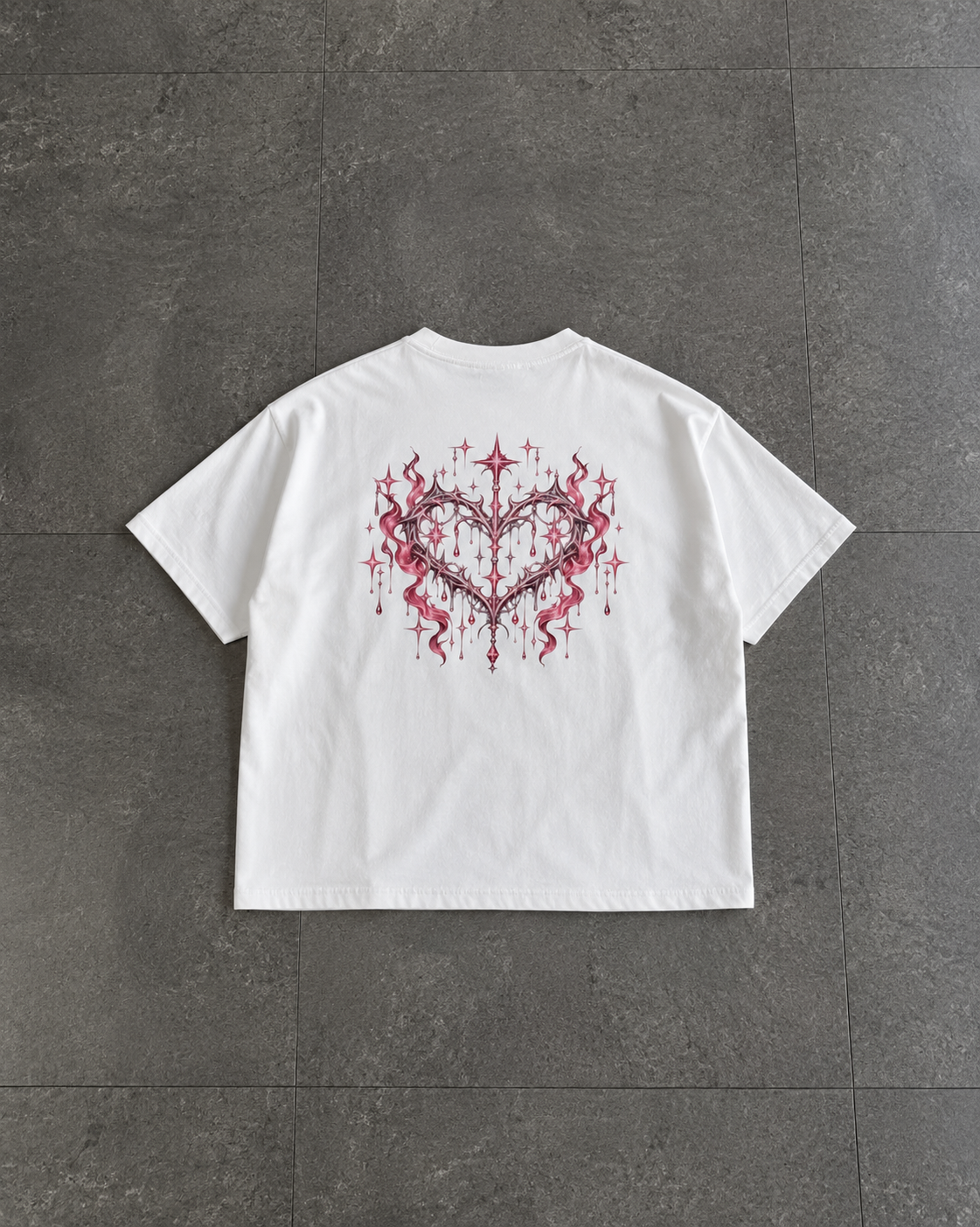 A white short-sleeve t-shirt laid flat on a dark gray tiled floor, featuring a red and black heart-shaped graphic with lightning bolts on the back.

Color: White Back