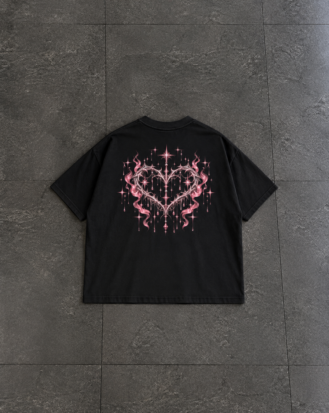 A black short-sleeve t-shirt laid flat on dark gray tiled flooring, featuring a large pink and white graphic of a heart with flames and stars on the back.

Color: Black Back