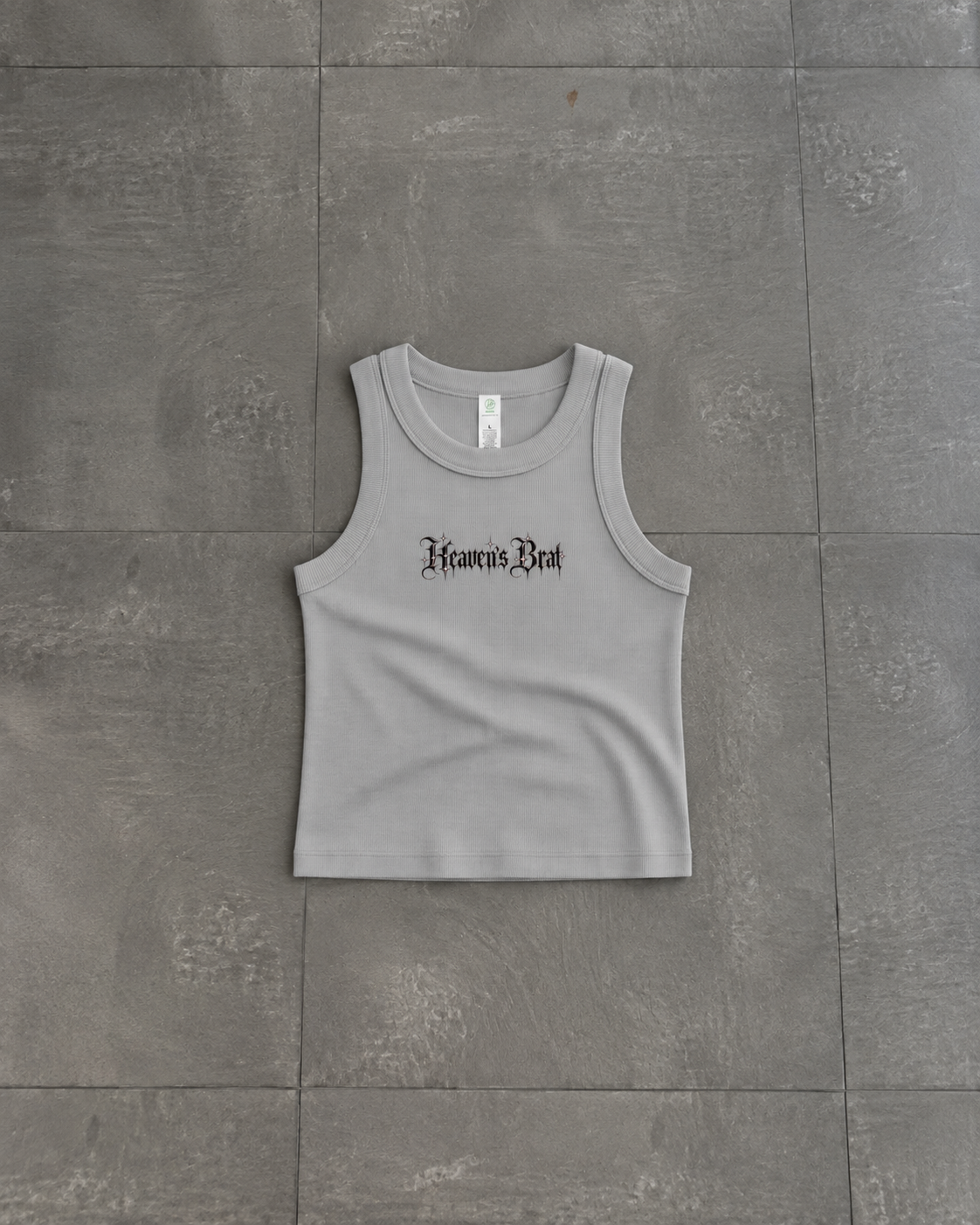 A light gray sleeveless crop tank top with 'Heaven's Rest' printed in a black gothic font across the chest, laid flat on a gray tiled floor.

Color: Storm Front