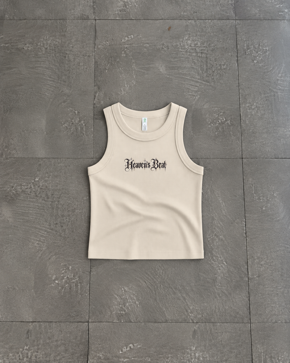 A beige ribbed tank top with 'Hear No Evil, See No Evil, Speak No Evil' printed in black gothic font on the chest, laid flat on a gray tiled floor.

Color: Bone Front