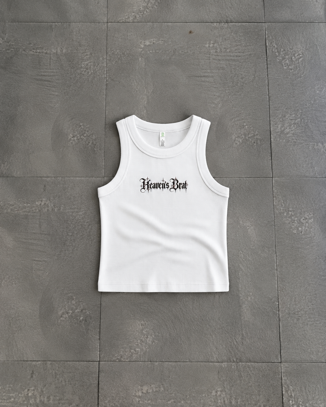 A white sleeveless tank top with 'Hear No Evil' printed in a black gothic font across the chest, laid flat on a gray tiled surface.

Color: White Front