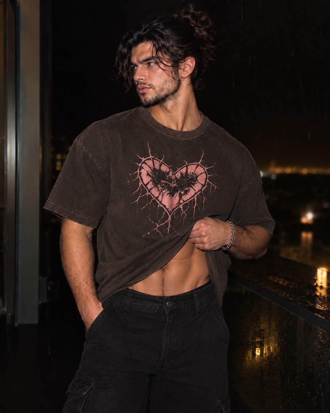 A man wearing a faded brown graphic t-shirt with a pink heart design, paired with black cargo pants, standing on a wet balcony at night.

Color: Vintage Black Front