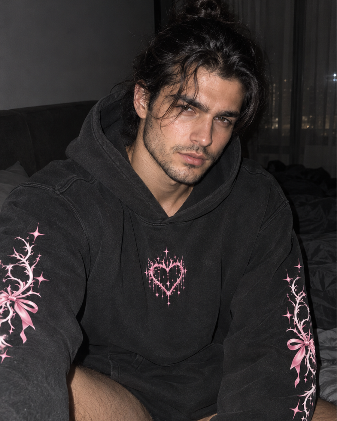 A man wearing a black hooded sweatshirt with pink graphic prints on the chest and sleeves, photographed in a dim indoor setting.

Color: Dyed Black Rock Front