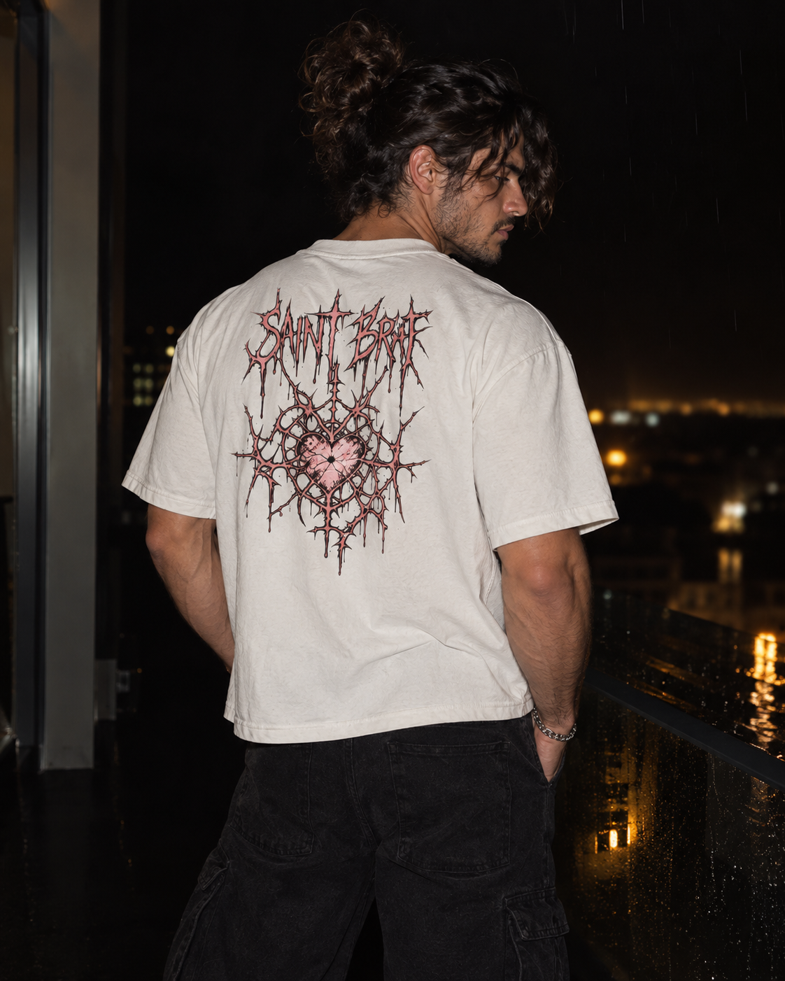 A man wearing a white t-shirt with a large, detailed black and pink graphic on the back, standing on a balcony at night.

Color: White Back