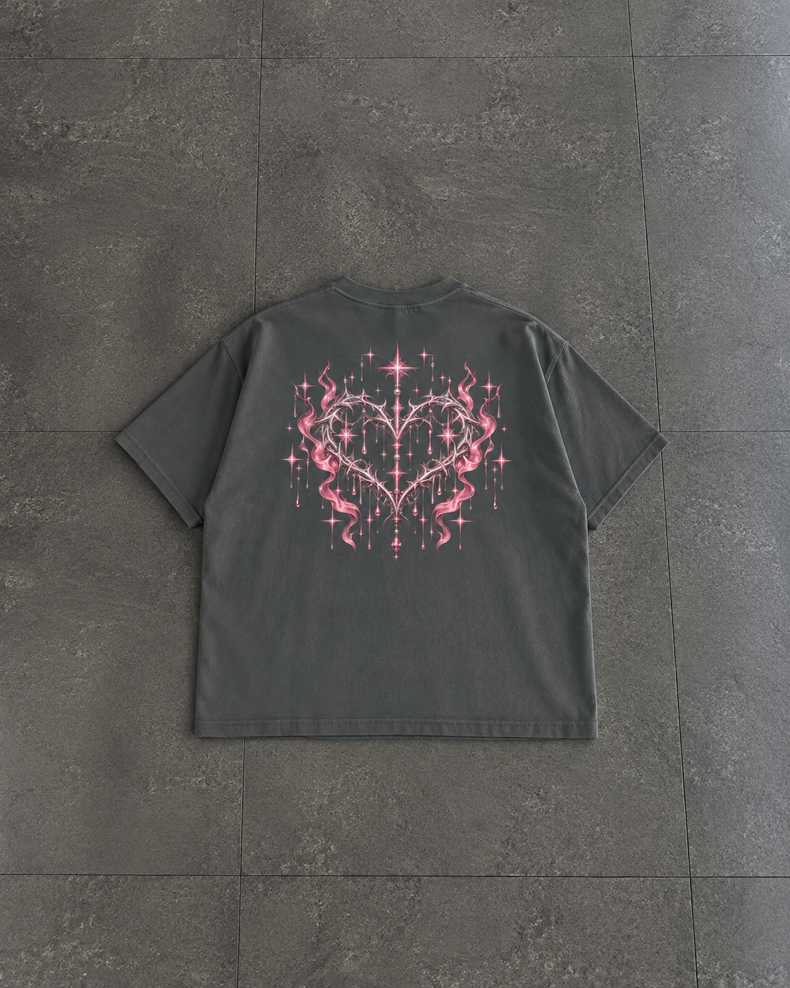 A dark gray short-sleeve t-shirt laid flat on a dark gray tiled floor, featuring a large pink and white graphic of a heart with stars and lightning bolts on the back.

Color: Pepper Back