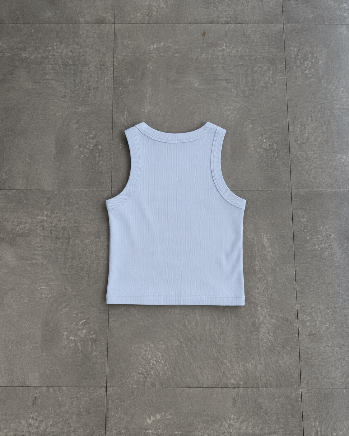 A light blue sleeveless tank top laid flat on a gray tiled floor.

Color: Powder Back