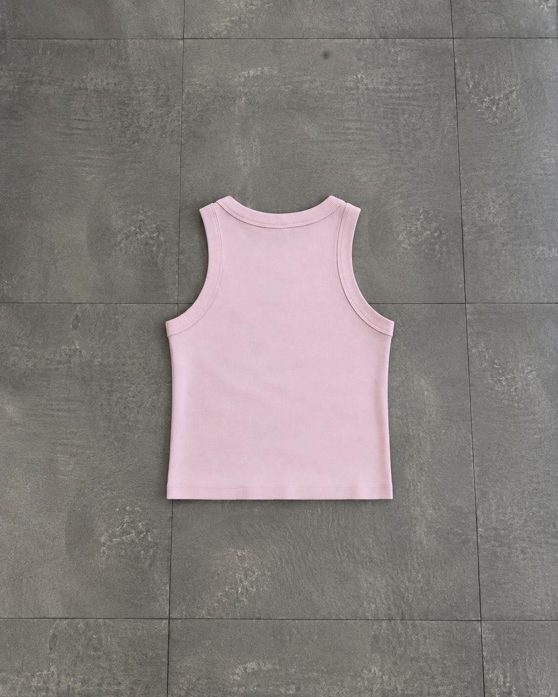 A light pink sleeveless tank top laid flat on a dark gray tiled floor.

Color: Orchid Back