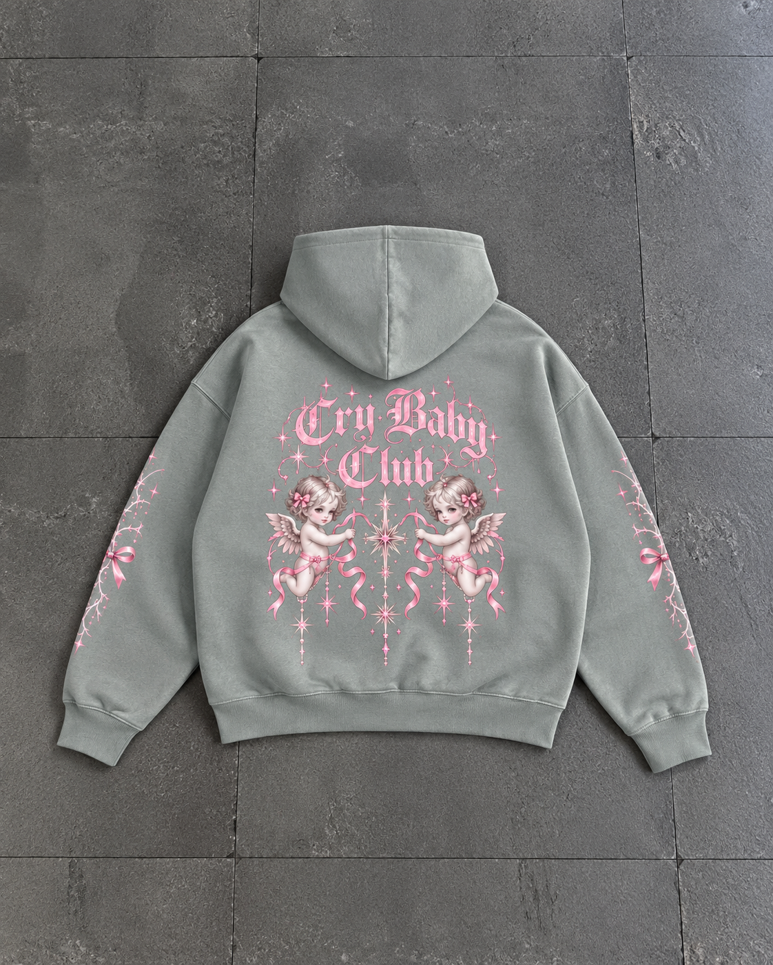 A sage green hoodie shown from the back, featuring a pink graphic print with the text 'Cry Baby Club' and cherub illustrations, laid flat on a dark gray tiled surface.

Color: Dyed Misty Grey Back