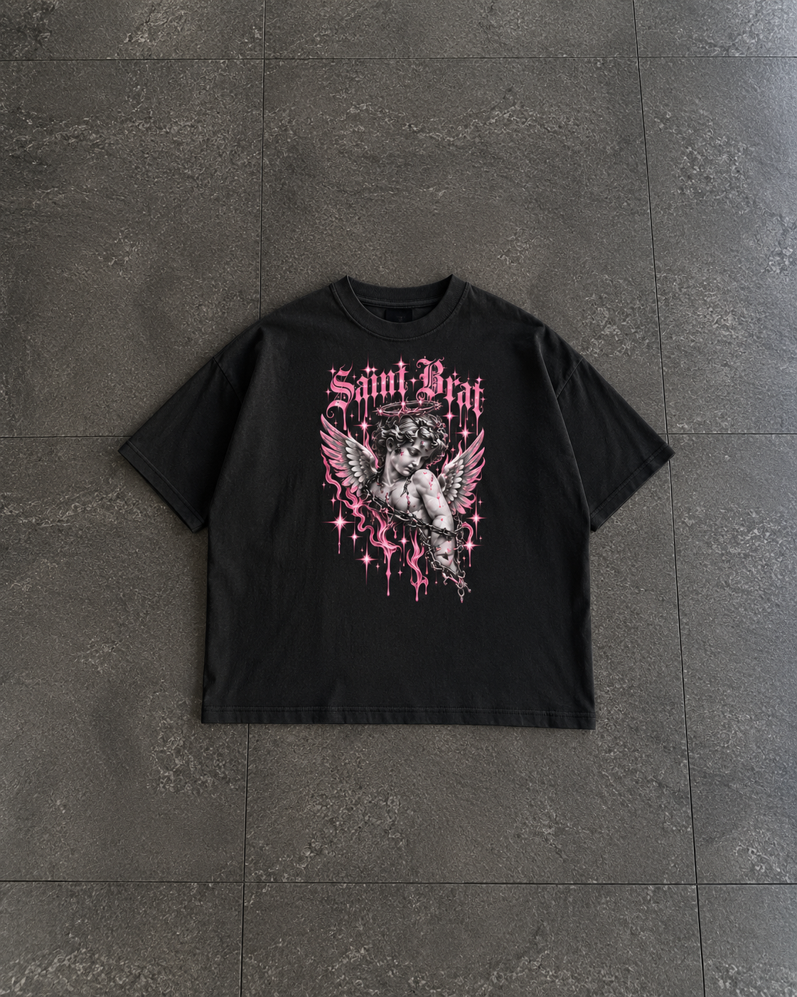 A black short-sleeve graphic t-shirt laid flat on a dark gray tiled floor. The shirt features a gothic-style pink and white graphic of a winged figure with the text 'Saint Brit' and 'HED' in a dripping font.

Color: Black Front