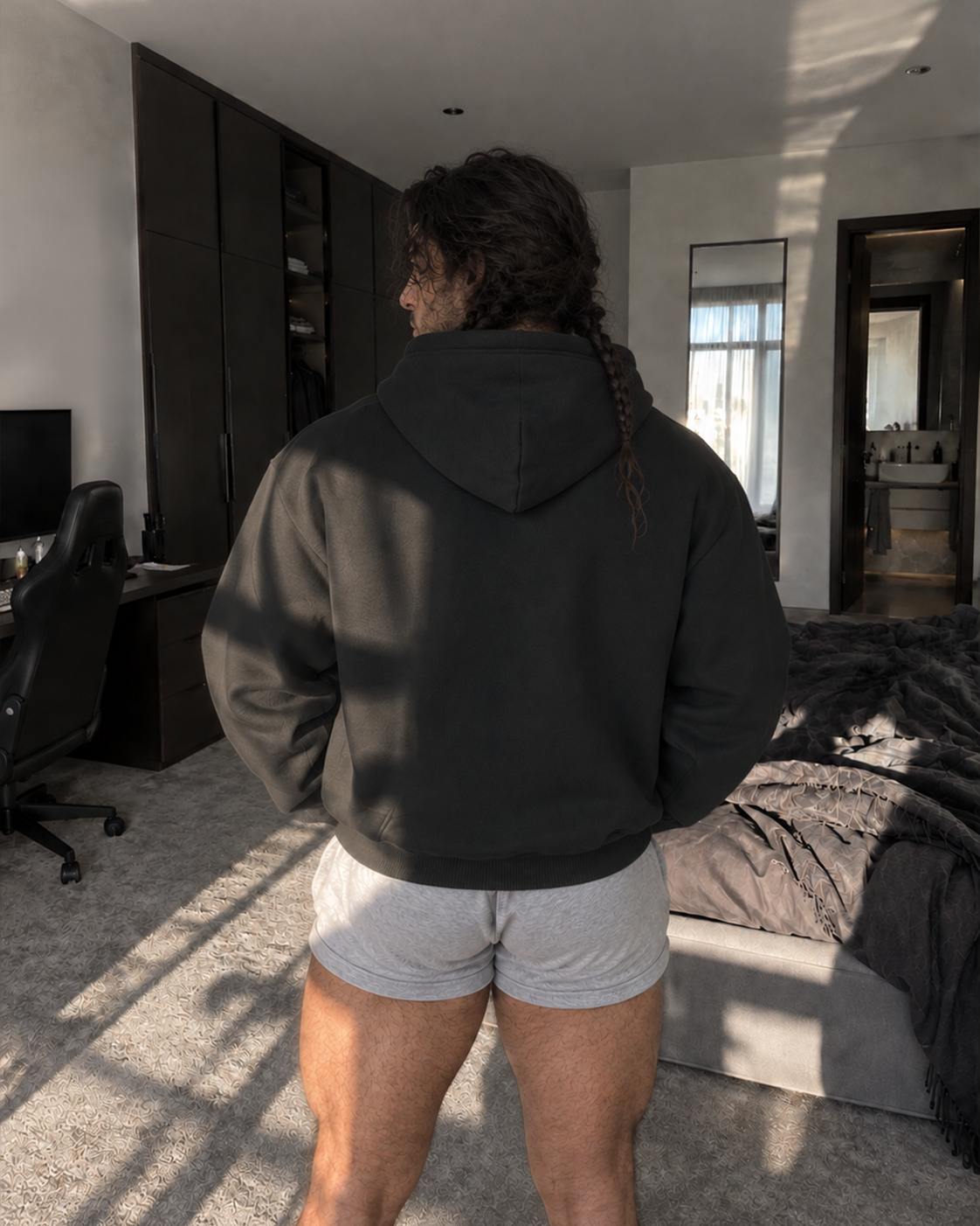 A person standing in a bedroom, viewed from behind, wearing a dark charcoal gray hoodie and light gray athletic shorts.

Color: Black Back 